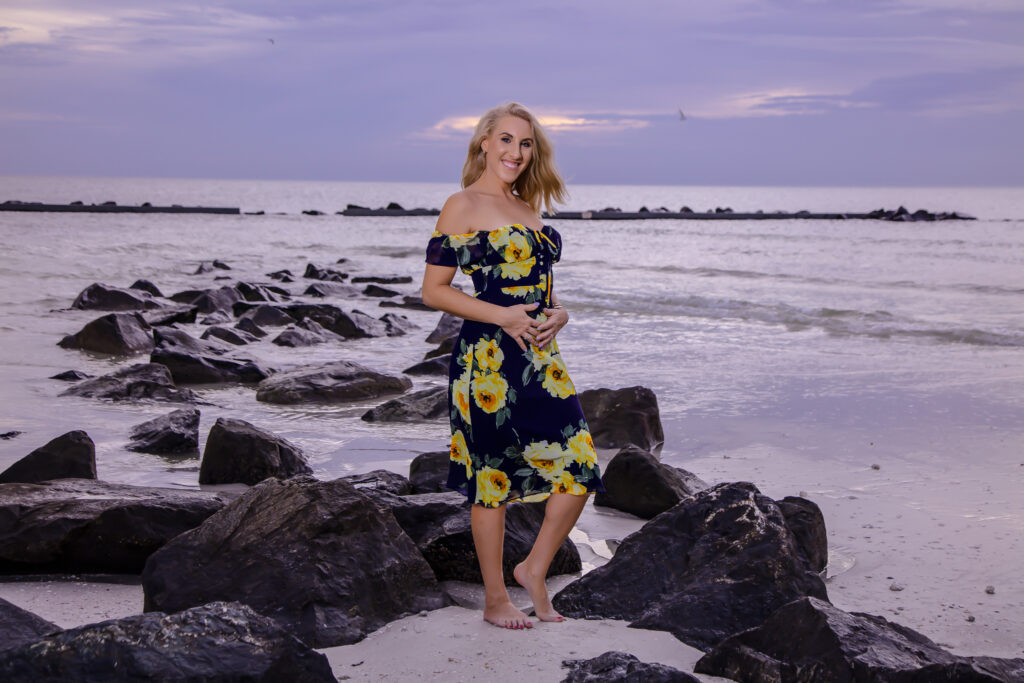 female standing on black rocks on the beach in the water