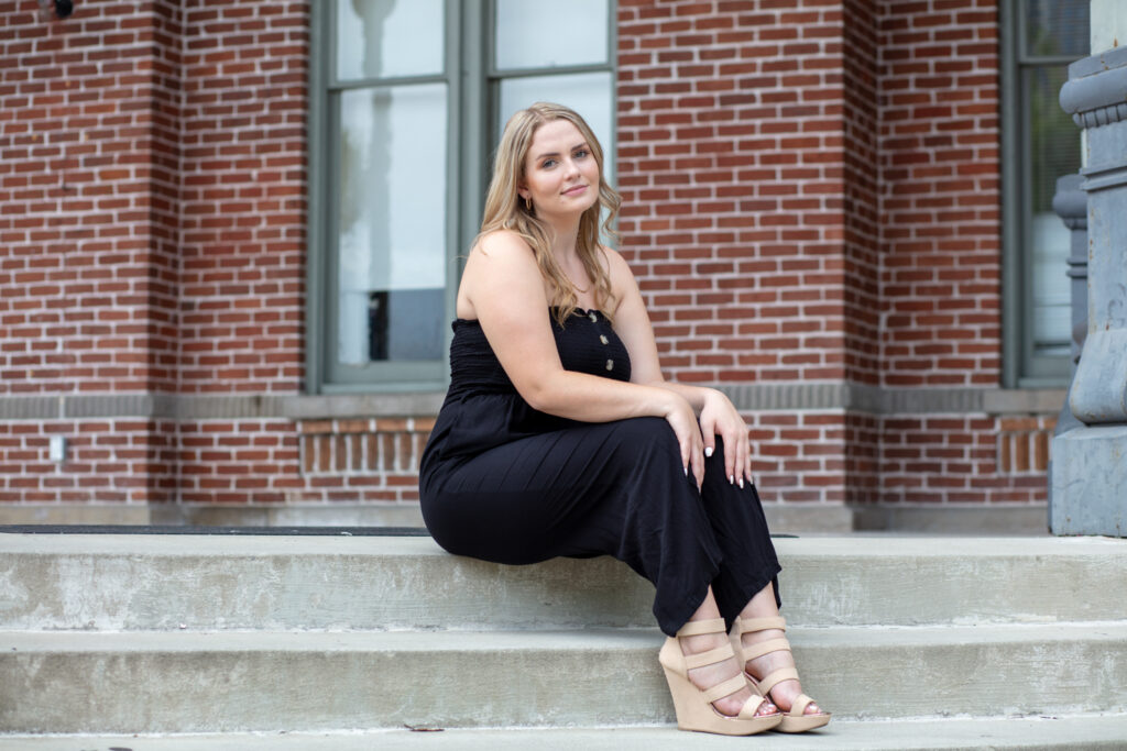 graduation girl sitting on concrete steps with brick wall background