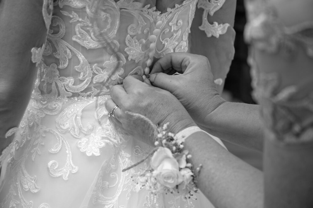 Brides mom buttoning the back of her dress