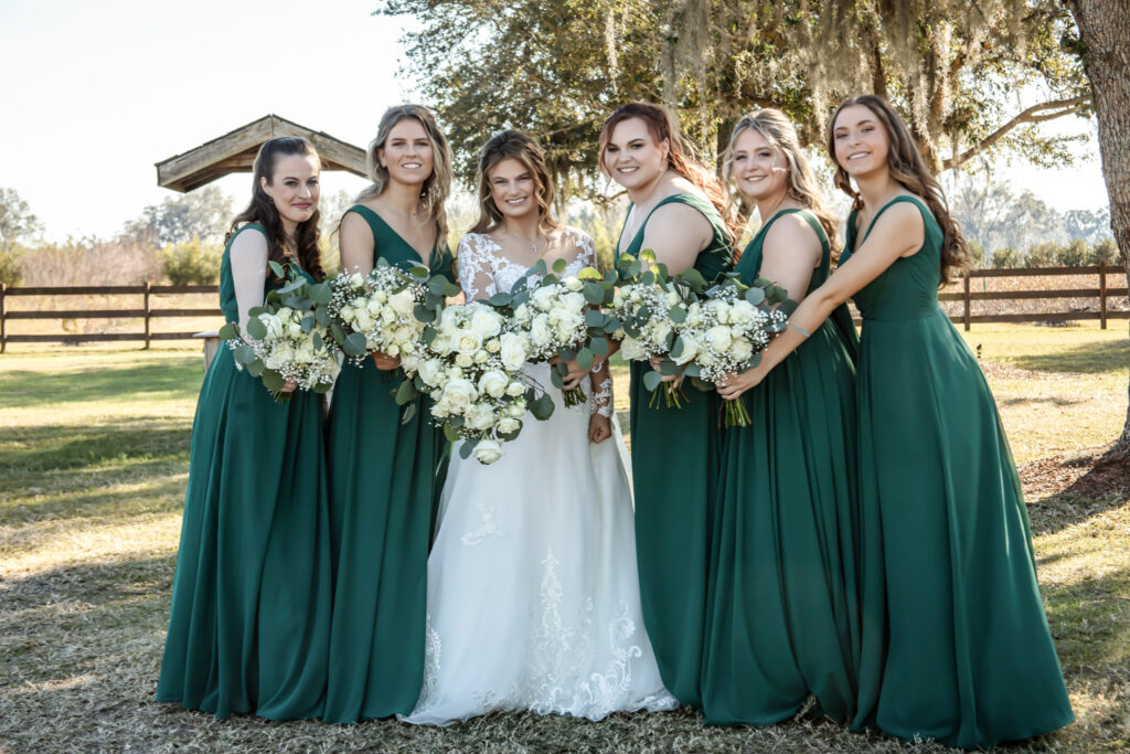 Bride with her bridesmaids and their flowers outside of a barn