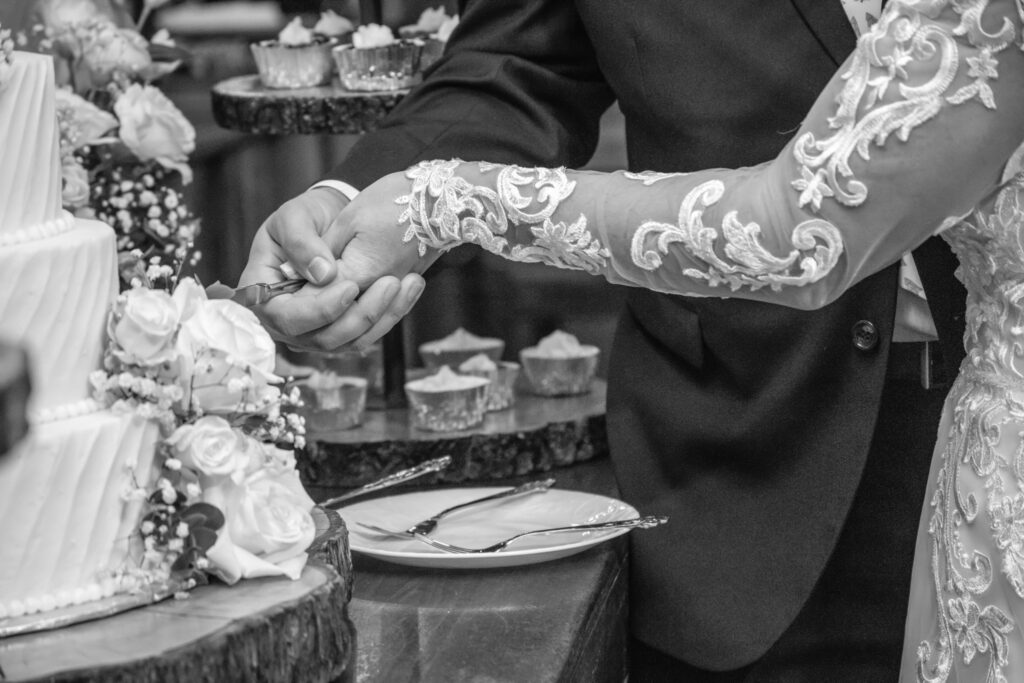Bride and grooms hands cutting wedding cake