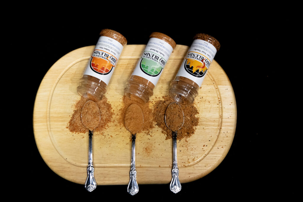 Nates BBQ seasonings on a wooden cutting board with spoons