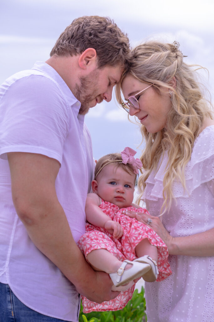 parents with their heads together and toddler girl in between them