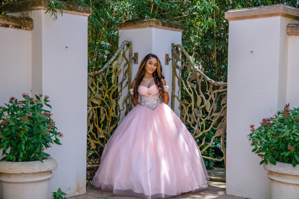 Quinceanera girl in her pink dress with trees in the background