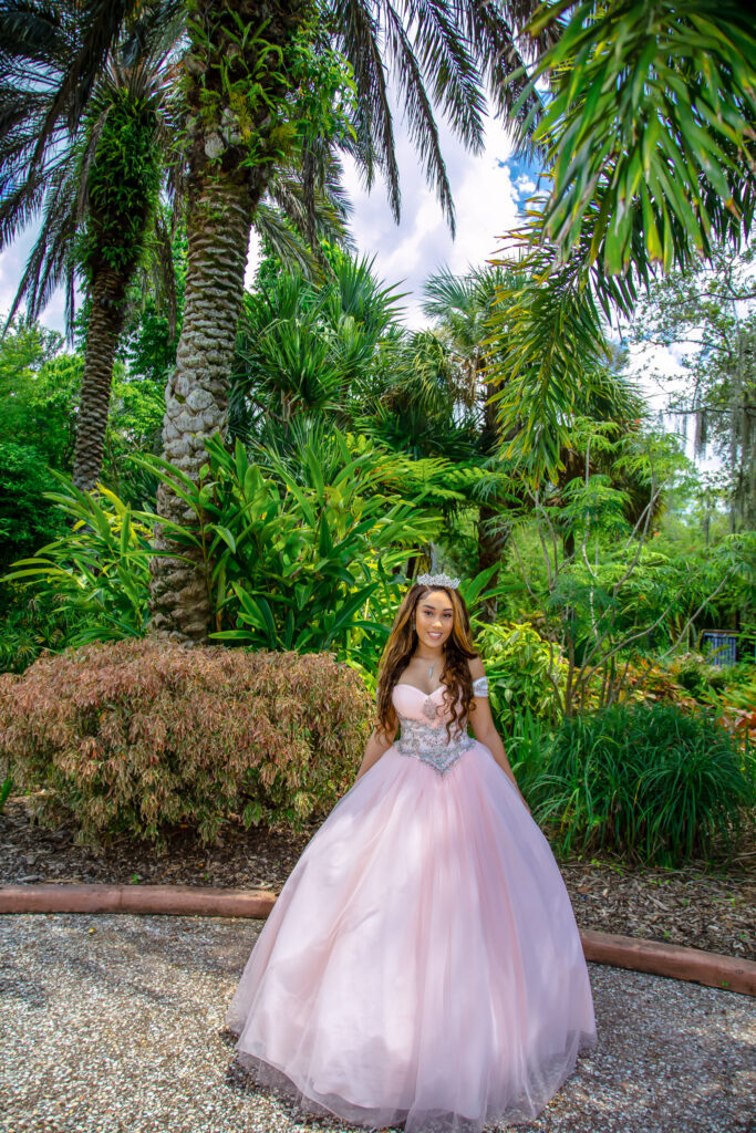 Quinceanera girl in her pink dress with trees in the background