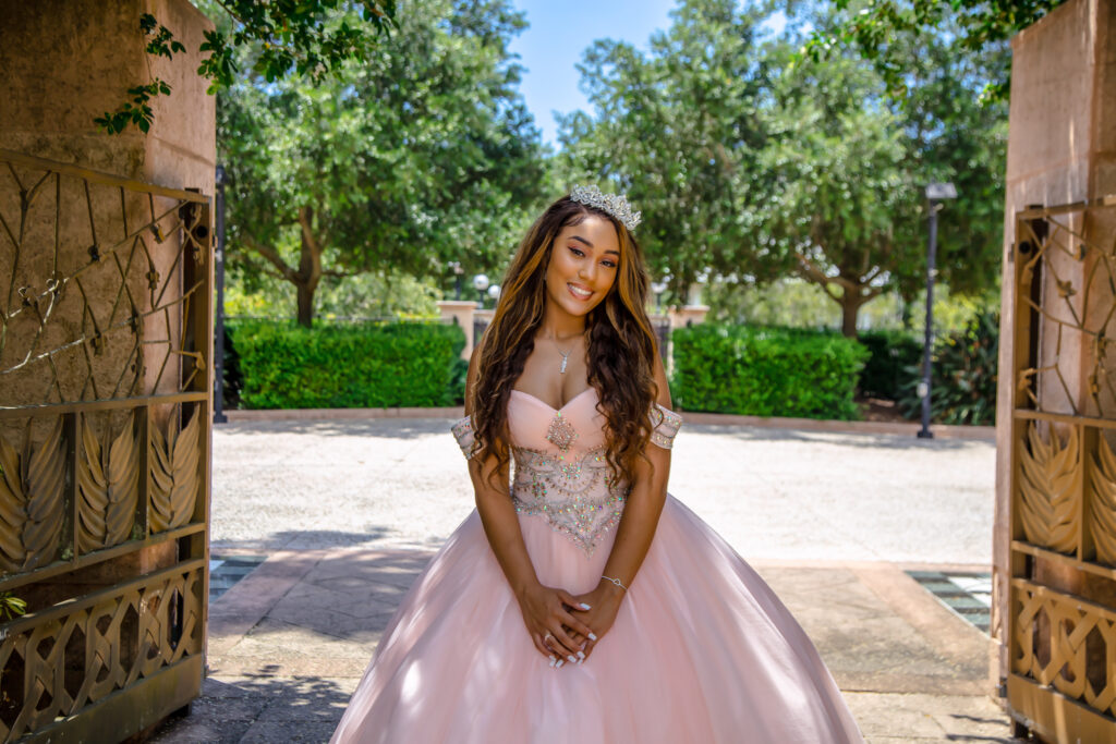 Quinceanera girl in her pink dress with greenery in the background