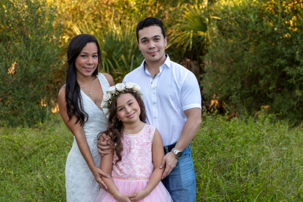 family of three in a grassy area