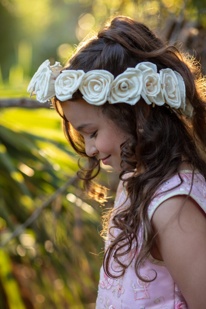 small girl child in her pink dress in front of a tree