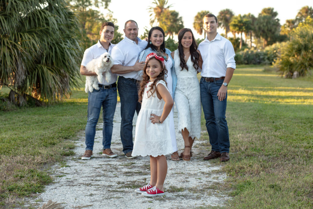 family of 6 on a grass and rock path at sunset