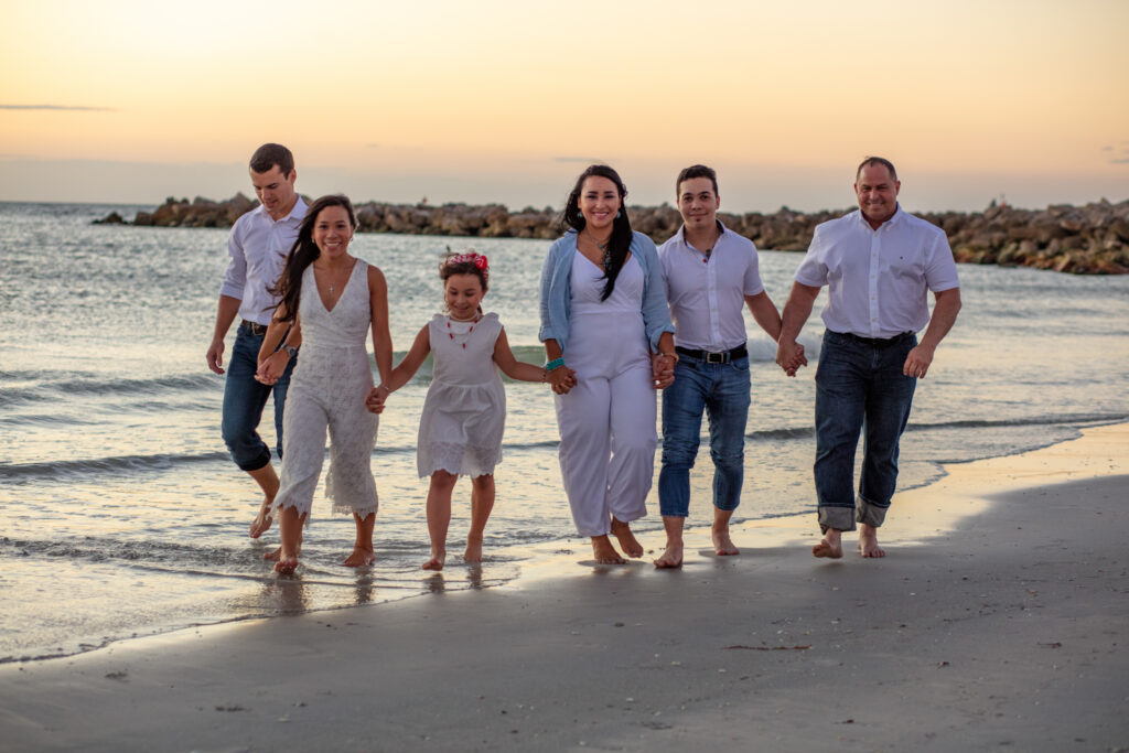 family of 6 walking on the beach at sunset