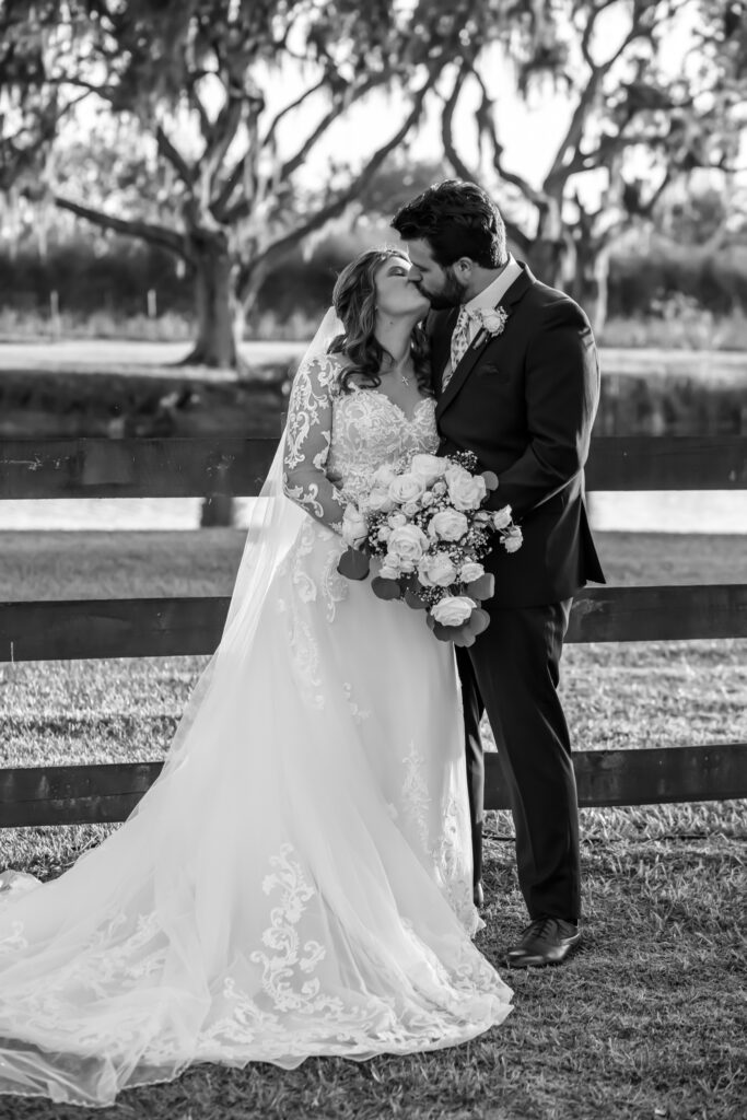 Bride and groom kissing in front of the wooden barn fence