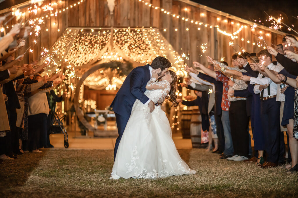 bride and groom kissing at the end of their sparkler exit at barn at night