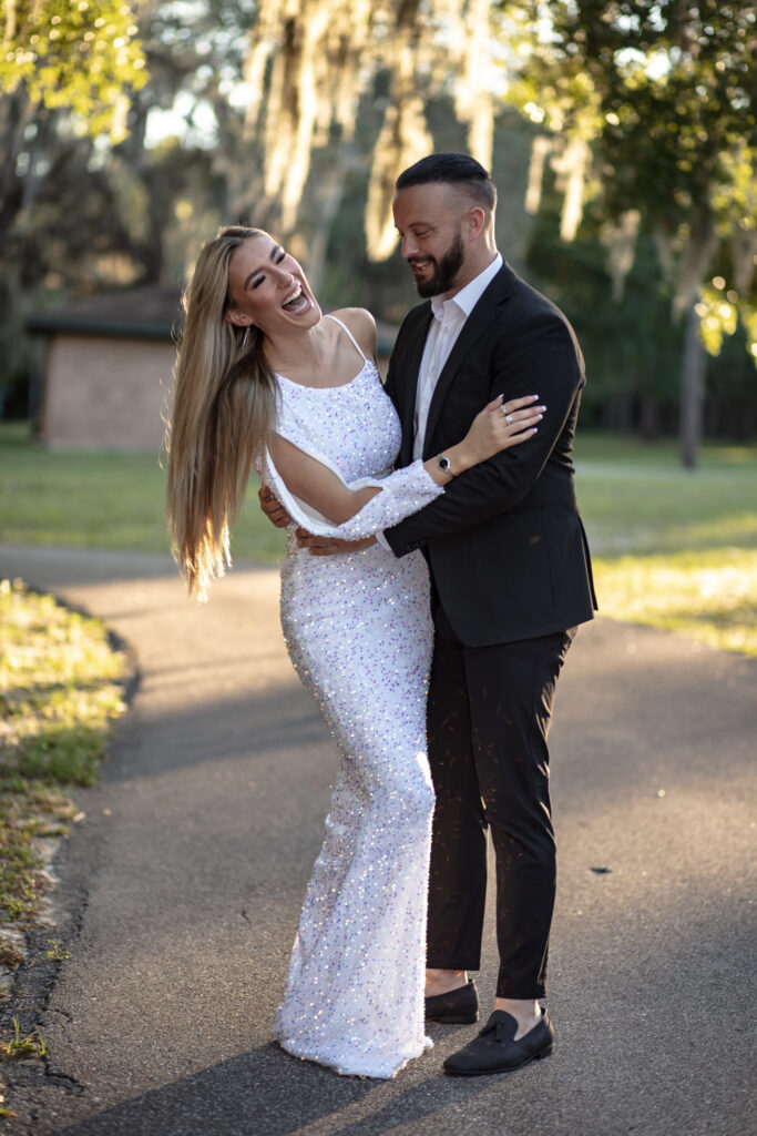 couple walking in the park laughing with the sunset behind them thru the trees