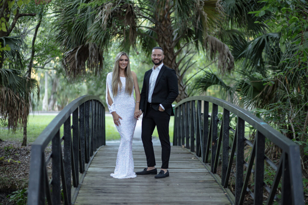 couple holding hands on a bridge in the park surrounded by trees