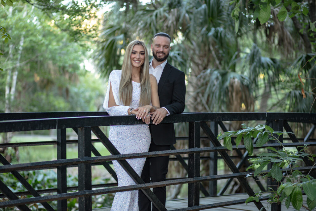 Couple standing on the side of a bridge in the park surrounded by trees