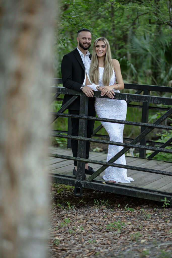 couple standing on a bridge looking at trees
