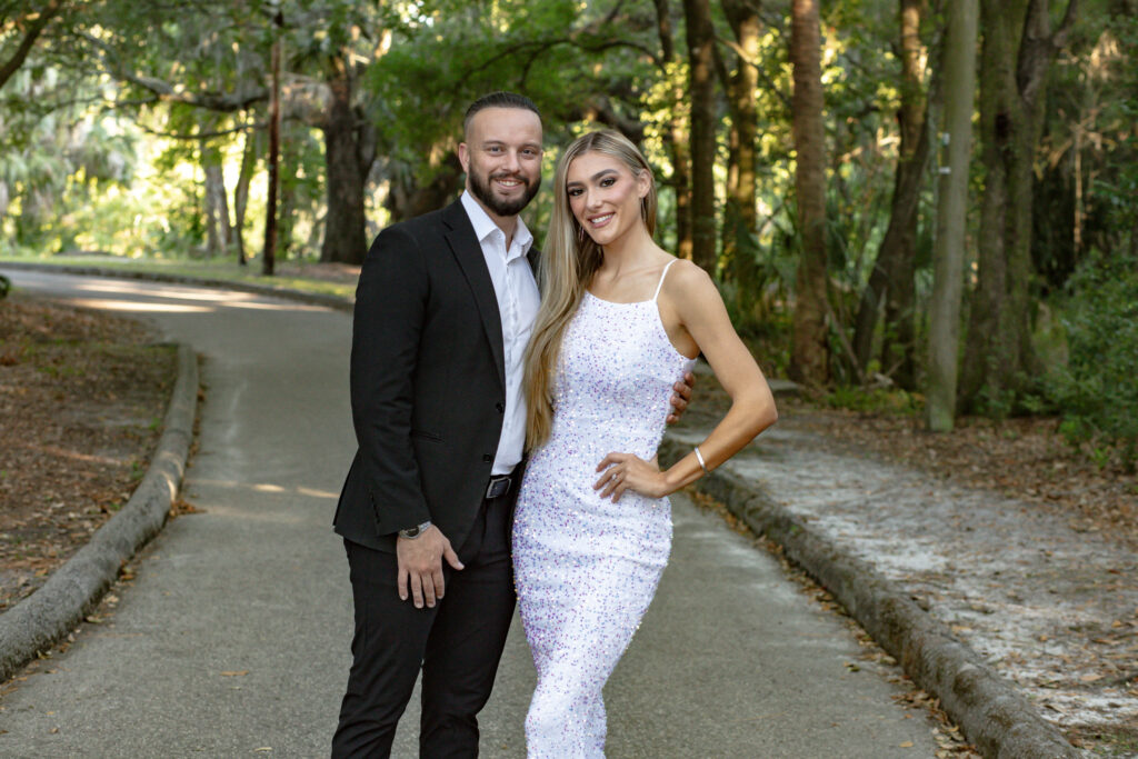 Couple holding each other on the concrete pathway in the park surrounded by trees