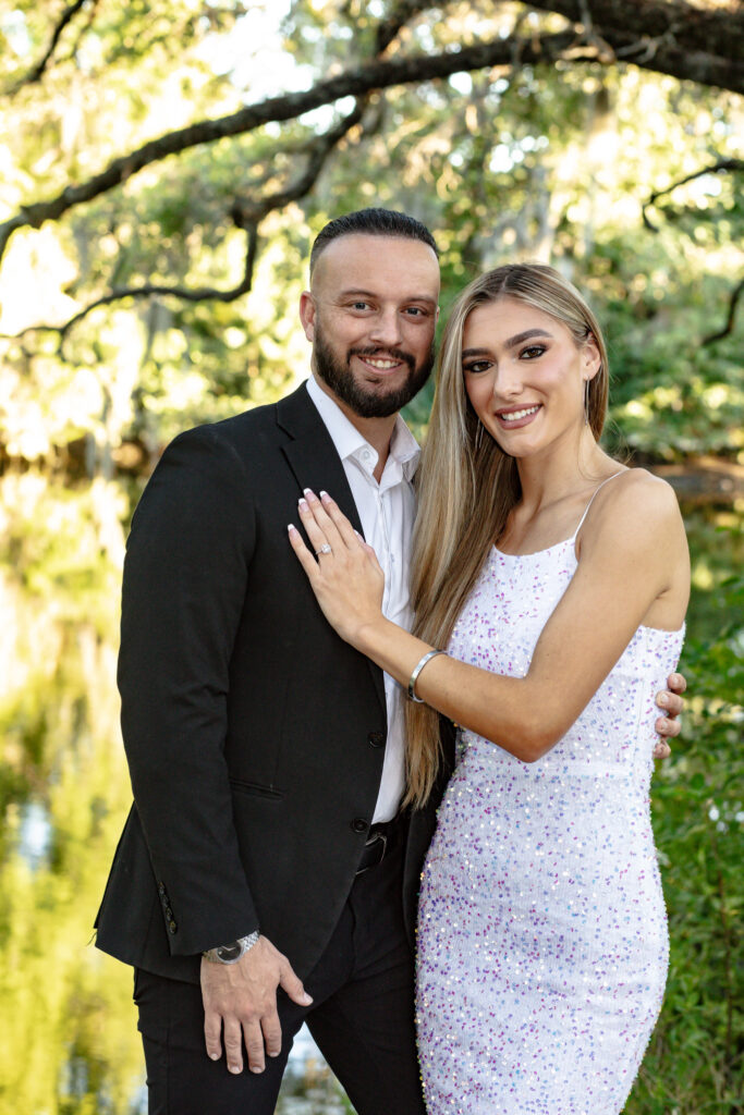 couple posing in the park at sunset by a river with trees