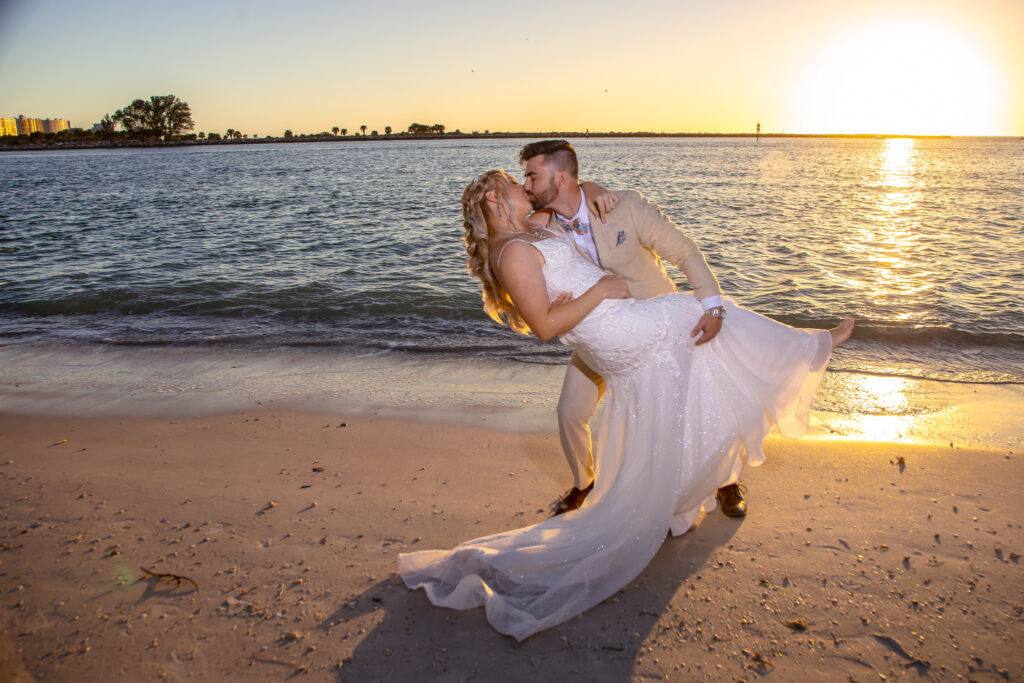 bride and groom kissing on the beach at sunset