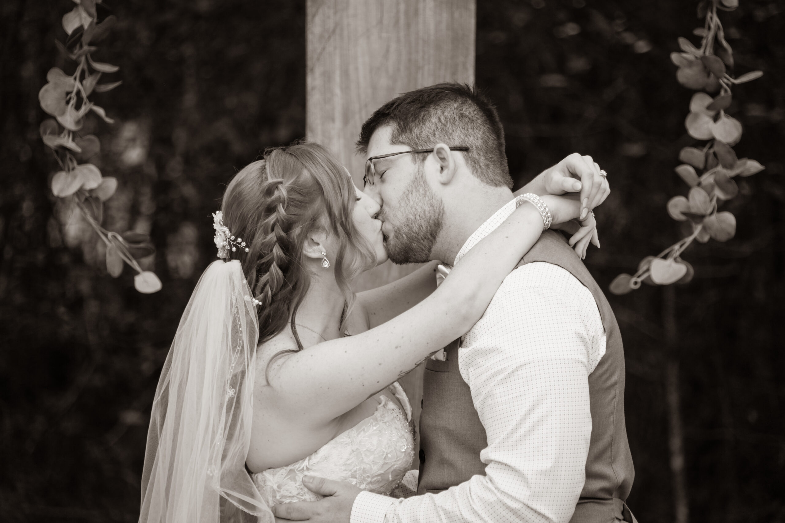 bride and groom kissing at the wedding ceremony altar, outdoors, black and white