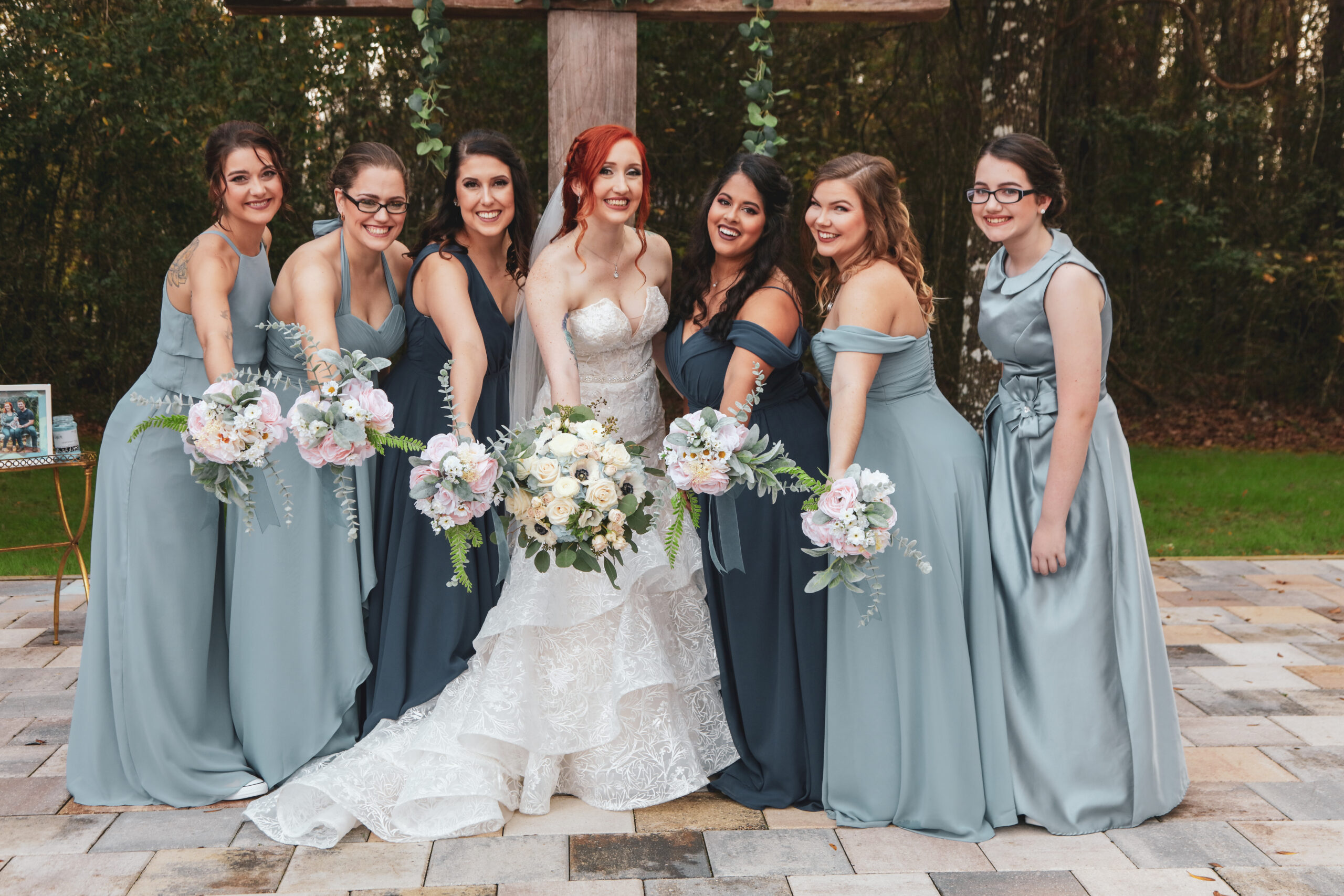 bride with bridesmaids posing at the wedding ceremony altar, outdoors