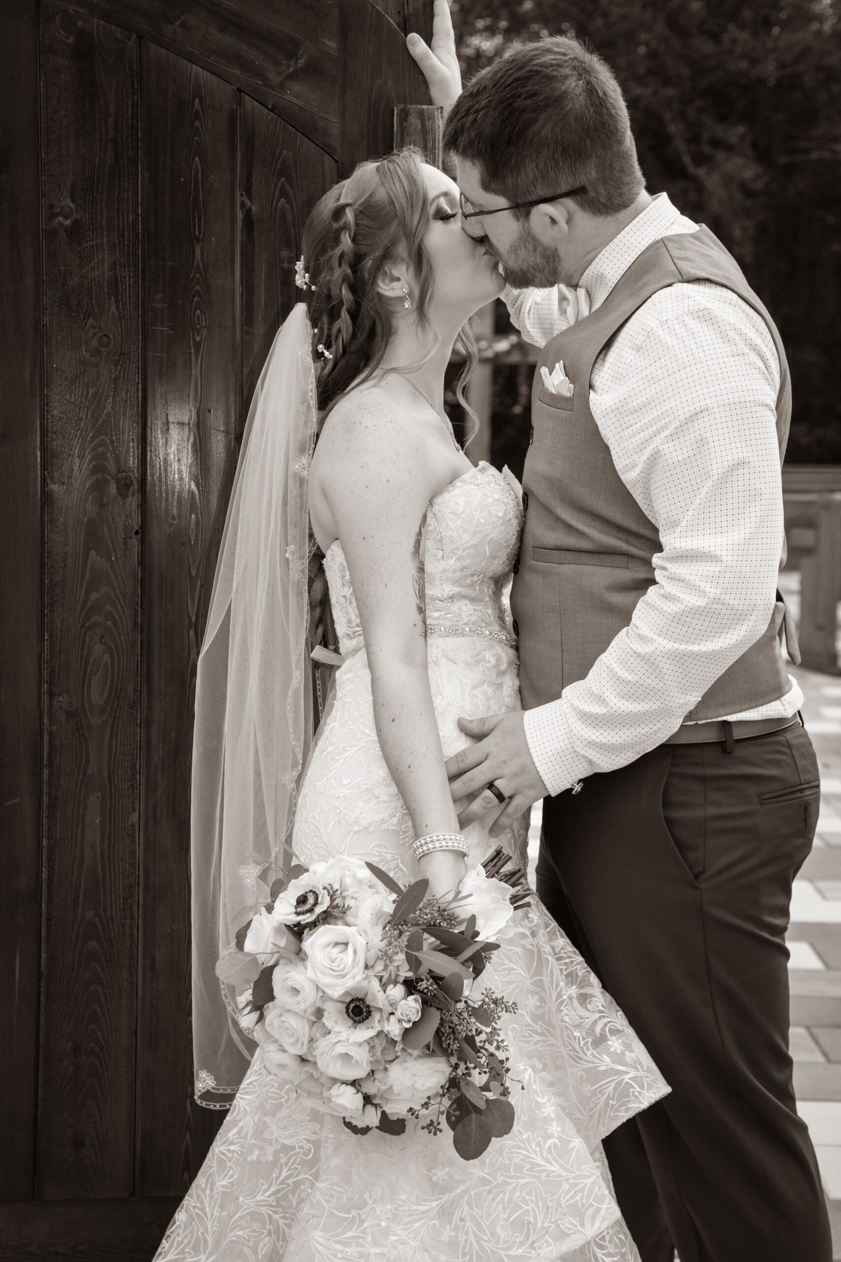 bride and groom kissing on the side of a wooden door