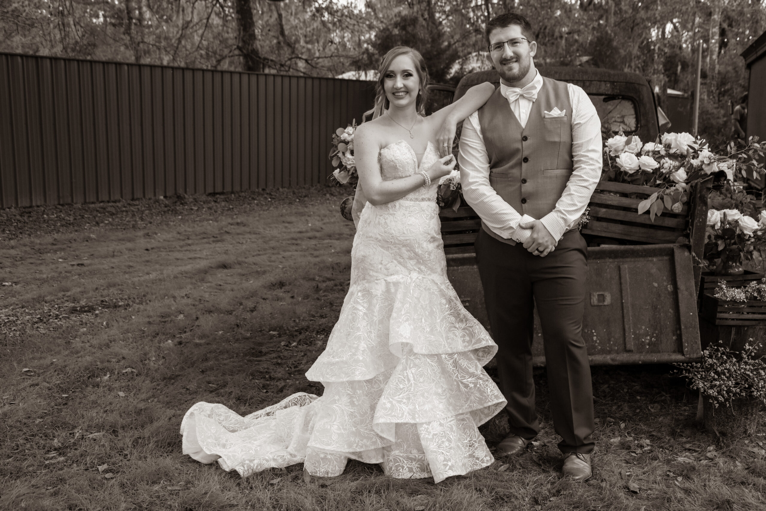 bride and groom posing behind an old pickup truck bed, black and white