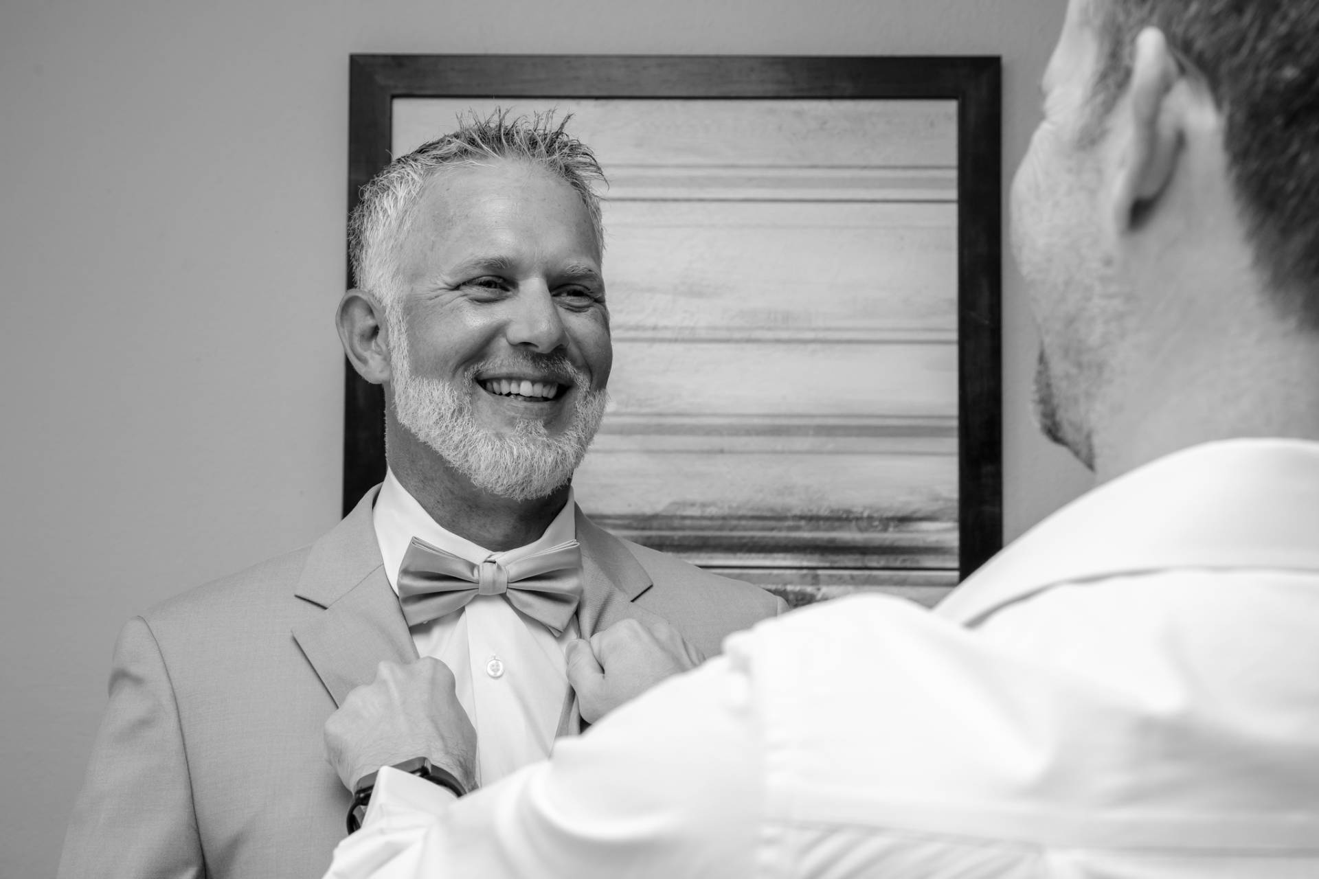 groomsmen putting the grooms bow tie on