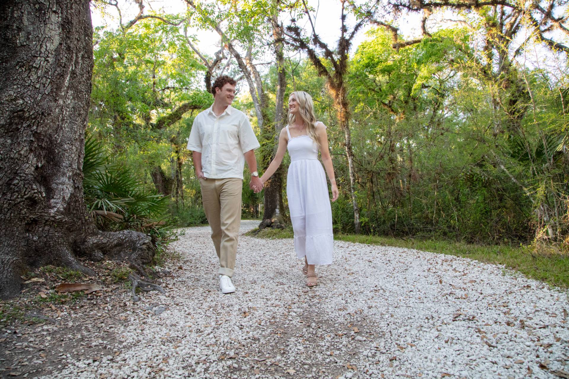 Couple holding hands walking on the rock path in the Lettuce Lake Park Tampa FL
