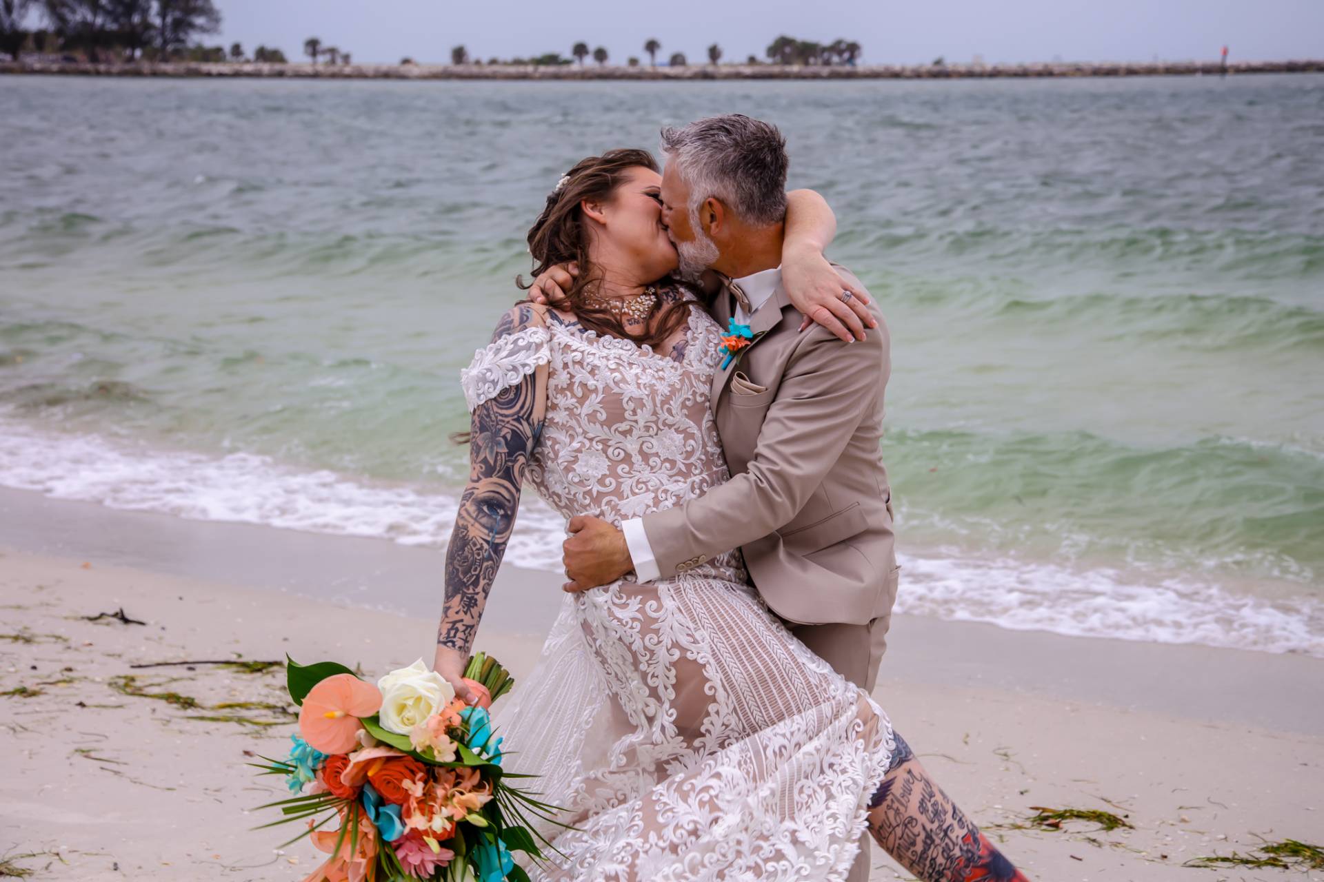 bride and groom kissing on the beach