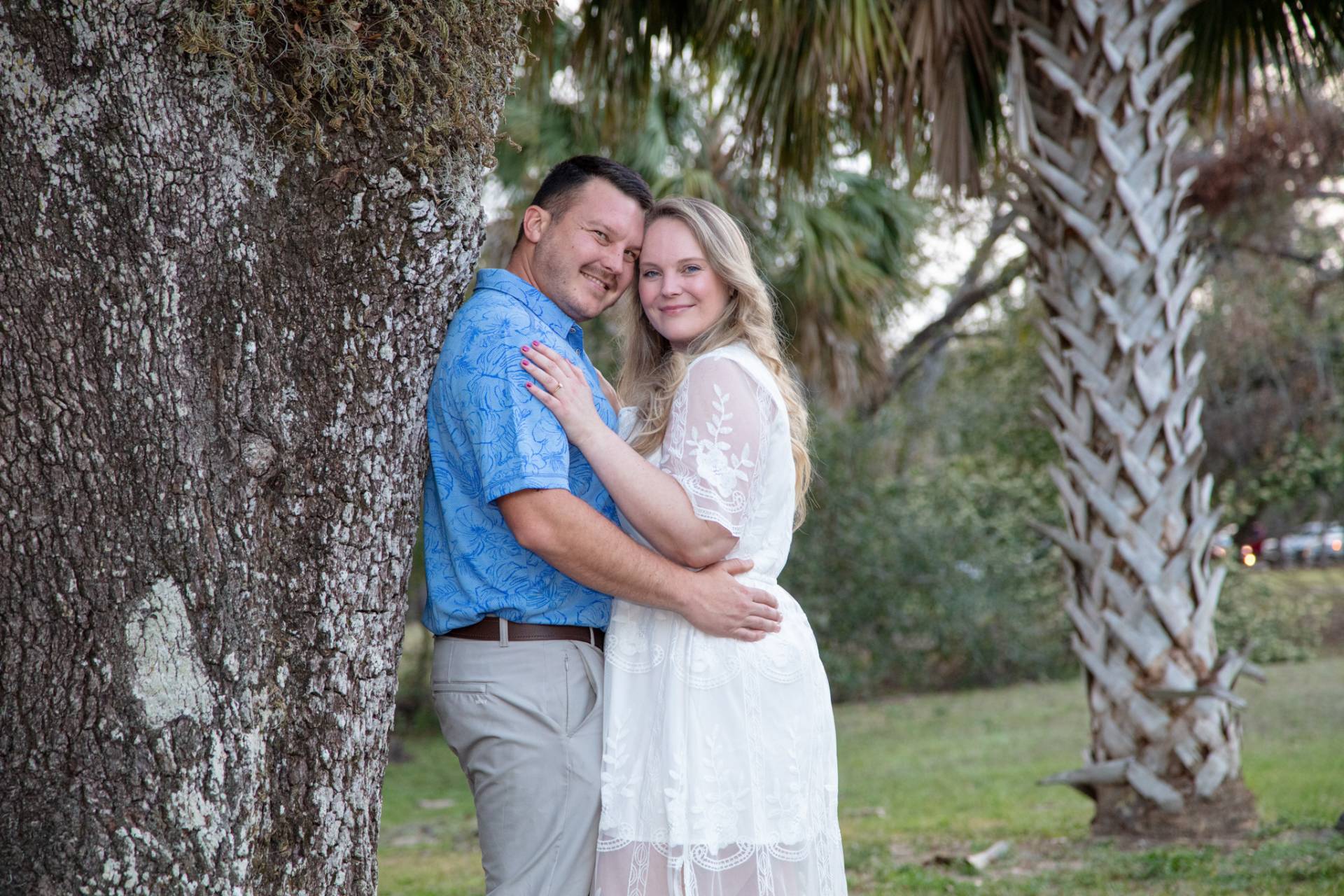 man with back against the tree with girl in front of him in the park