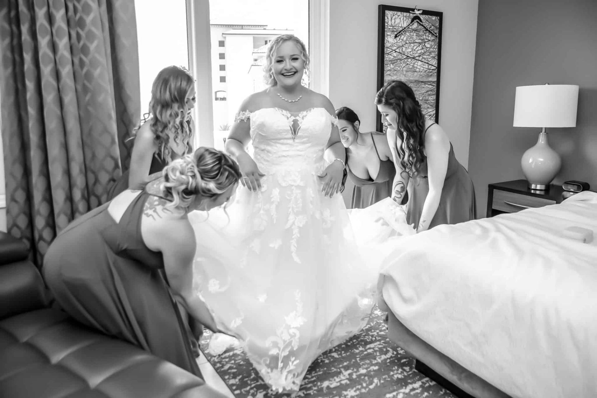 bridesmaids getting bride in her dress, black and white image