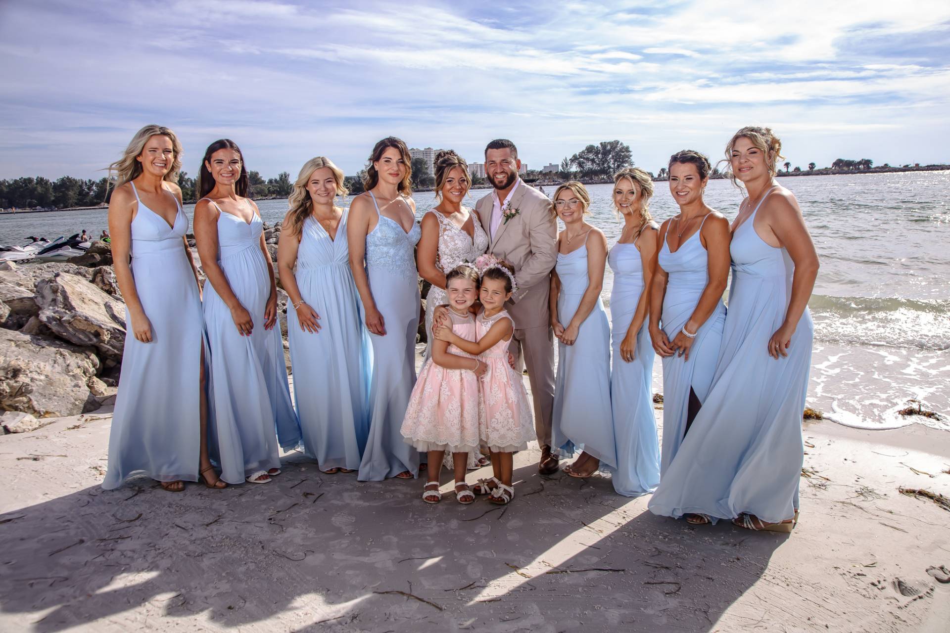 bride and groom with bridesmaids and flower girls on the beach