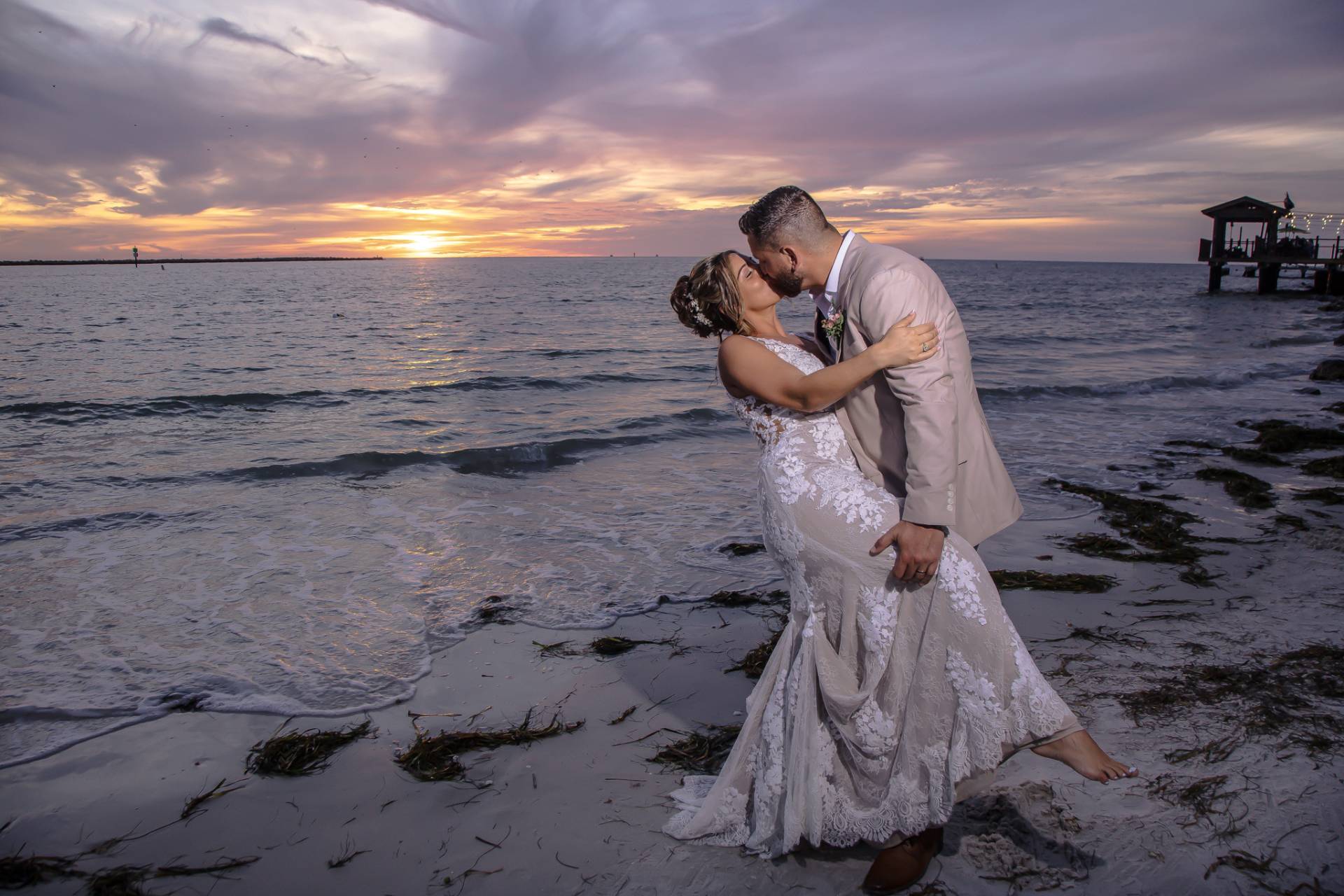 bride and groom kissing on the beach at sunset