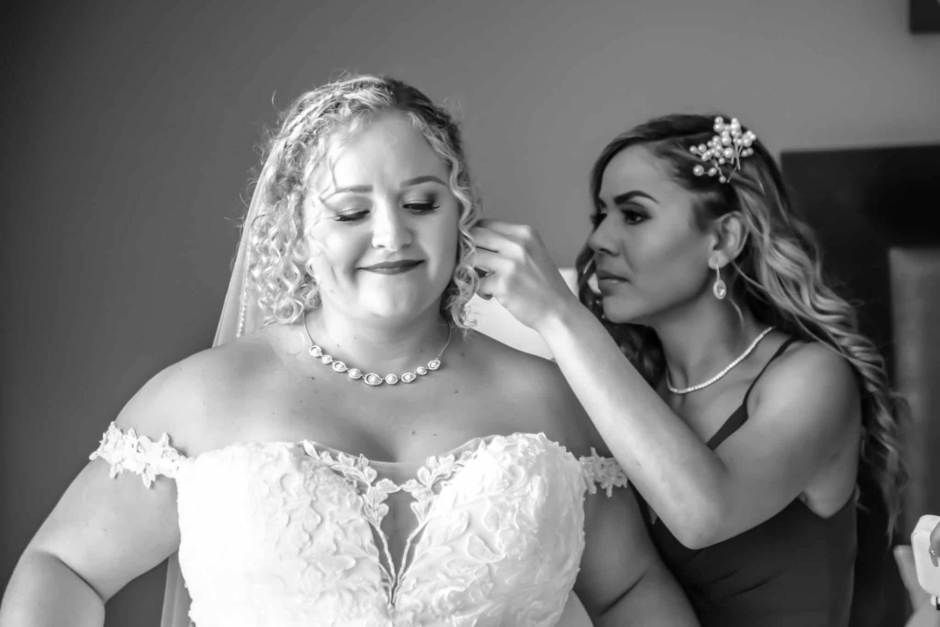 bride putting her earrings on, image in black and white