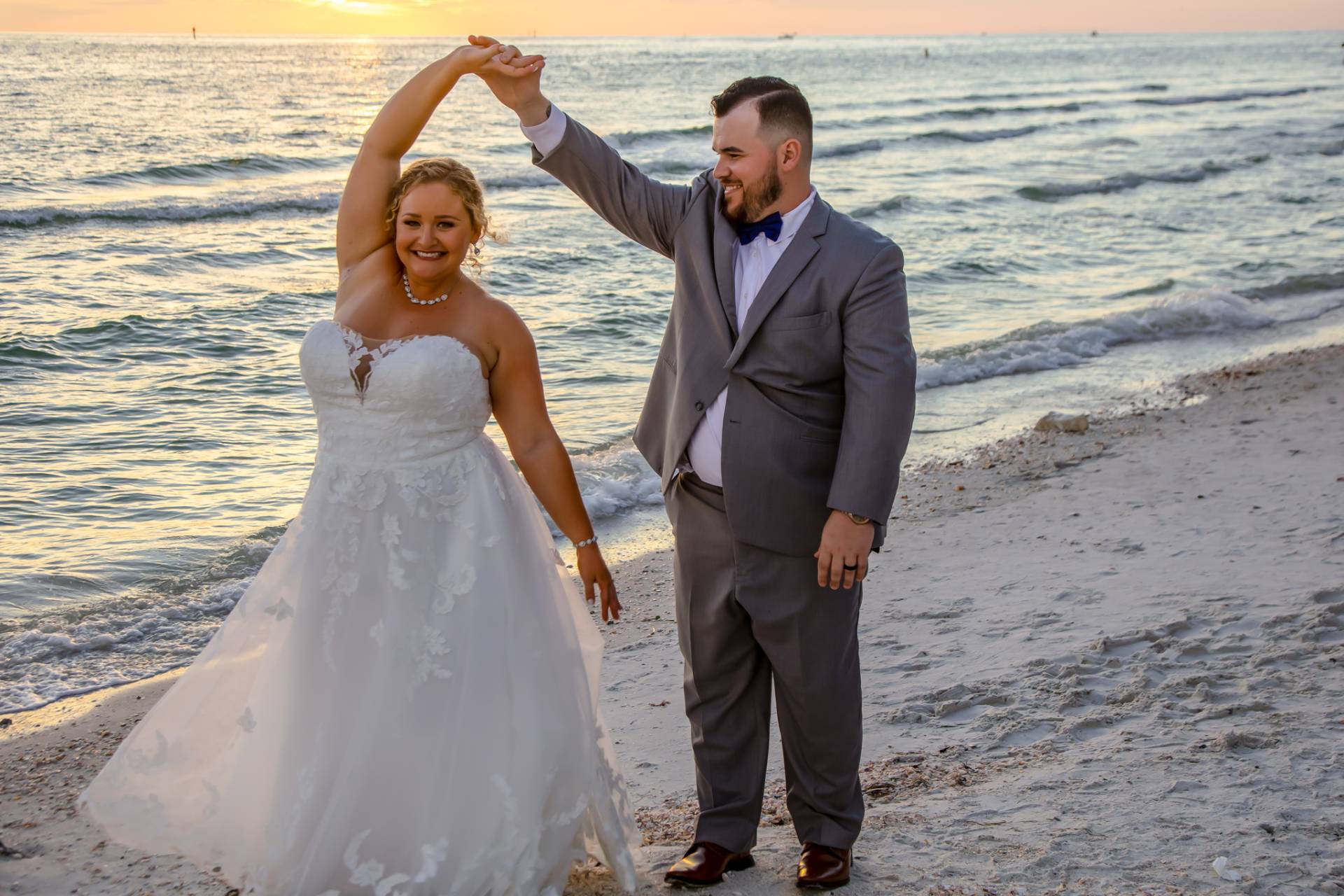 bride and groom dancing on the beach at sunset