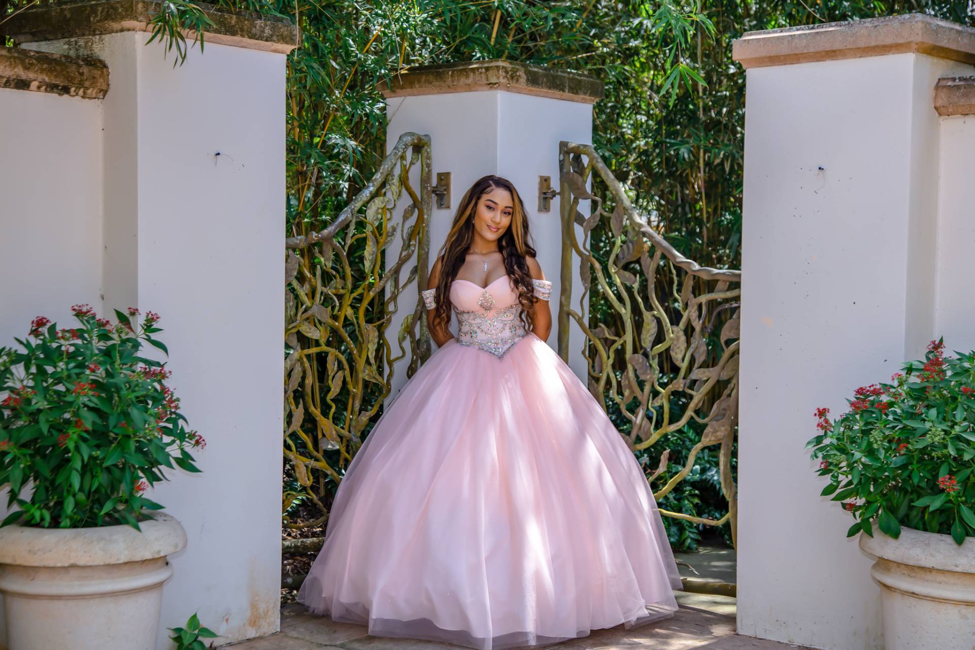 Quinceanera girl in her pink dress with trees in the background